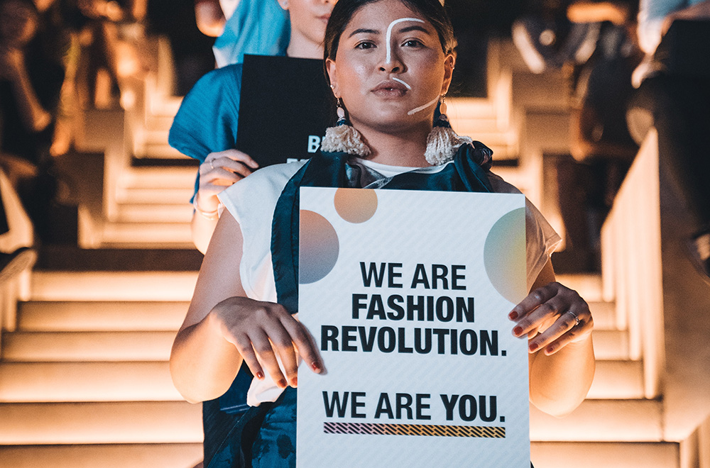 ragazza che manifesta per la fashion revolution con cartello in mano