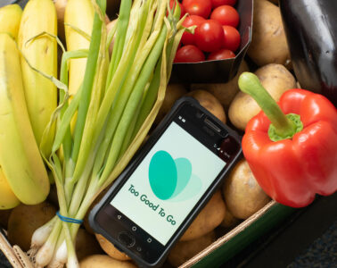 App To Good to Go su cellulare in un cesto di verdura. Spreco alimentare. Sostenibilità.