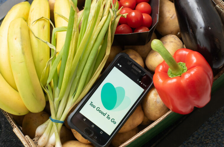 App To Good to Go su cellulare in un cesto di verdura. Spreco alimentare. Sostenibilità.